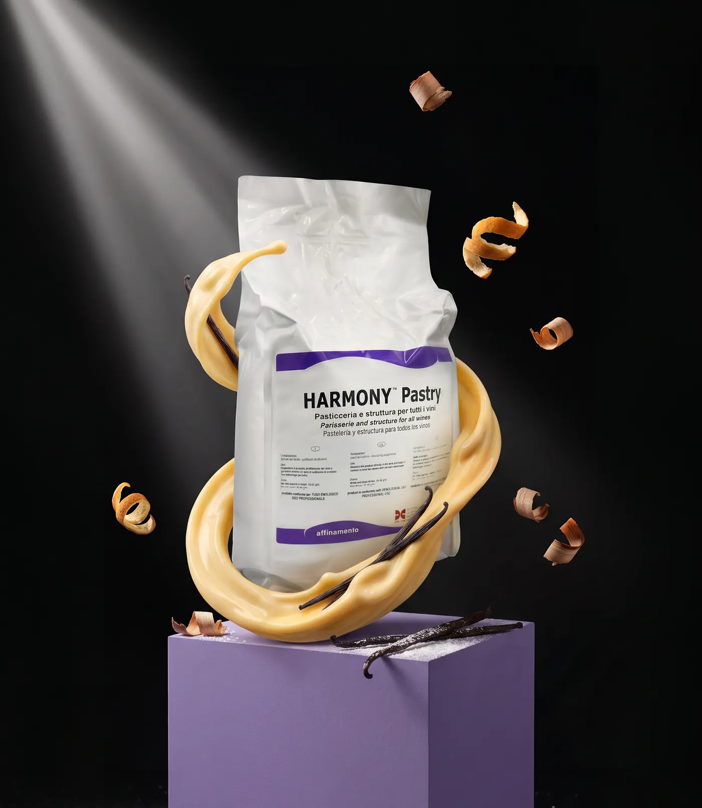 Confezione di Harmony Pastry su un cubo lilla, avvolta da un nastro di crema alla vaniglia, tra baccelli di vaniglia e trucioli di rovere